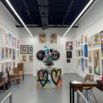 Bright contemporary exhibition space filled with colorful paintings, prints, and a central sculpture, showcasing the creative atmosphere visitors search for when looking for Art Galleries Near Me.