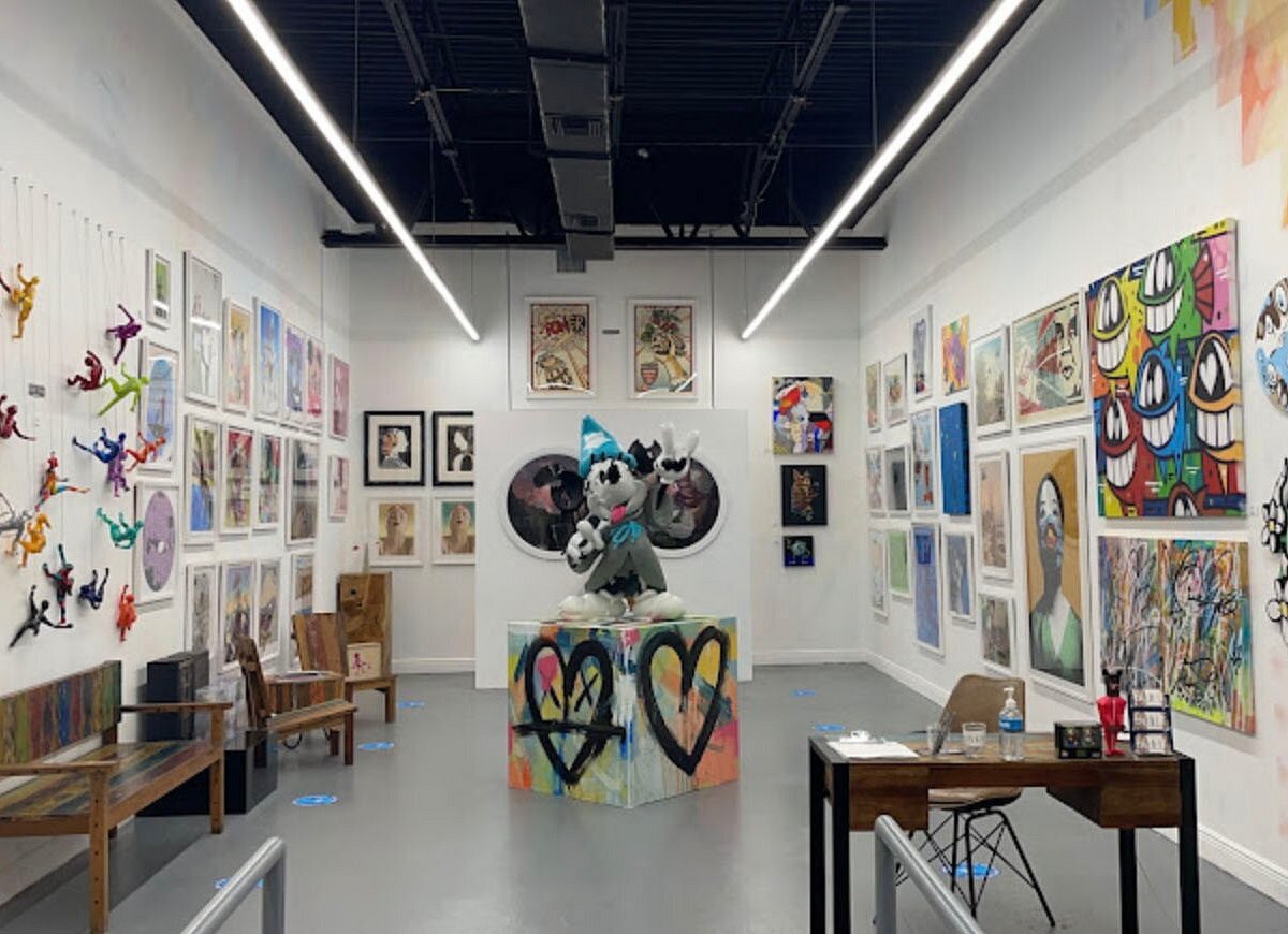 Bright contemporary exhibition space filled with colorful paintings, prints, and a central sculpture, showcasing the creative atmosphere visitors search for when looking for Art Galleries Near Me.