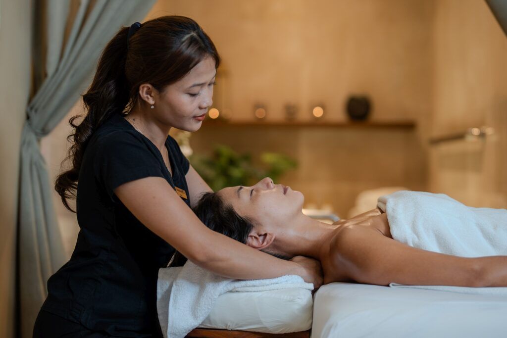 Massage parlor in Tysons Corner featuring a professional therapist providing a relaxing neck and shoulder massage to a client in a serene spa setting.